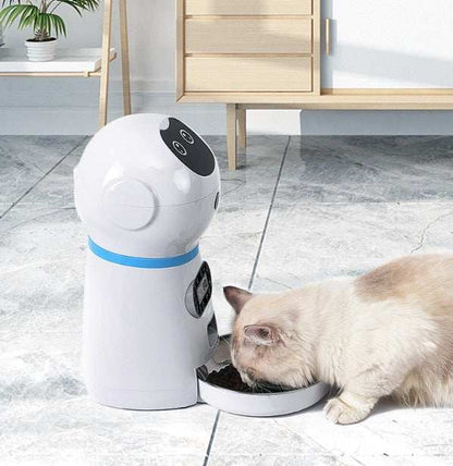 Pet robot feeder dispensing food to a cat on a tiled floor.