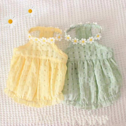 Two baby rompers, one yellow and one green, with floral headbands on a textured white background.