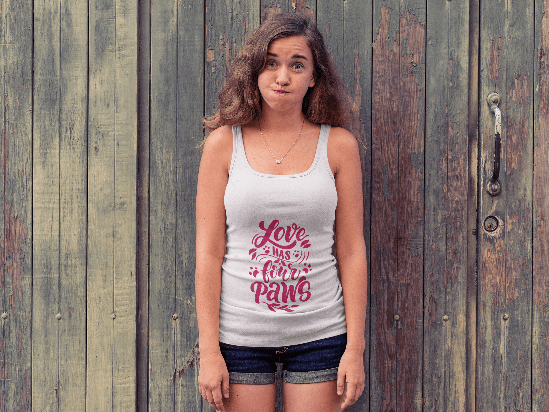 Printify white tank top with Love Has Four Paws graphic worn by woman standing in front of wooden doors