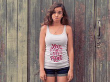 Printify white tank top with Love Has Four Paws graphic worn by woman standing in front of wooden doors