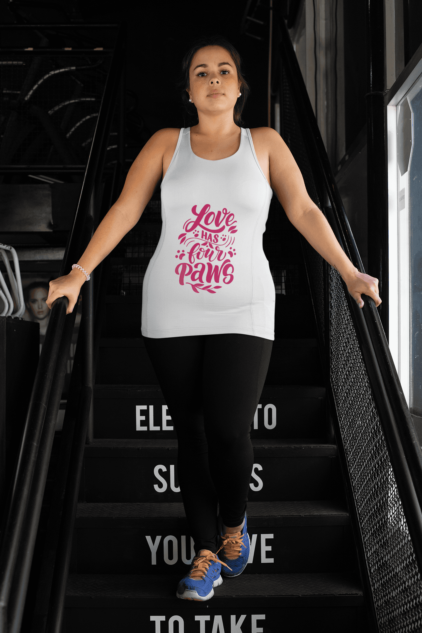 White tank top with pink Love Has Four Paws design worn by woman on stairs