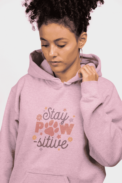 Stay Pawsitive Unisex Hoodie worn by woman model in pink with paw print graphic and kangaroo pocket