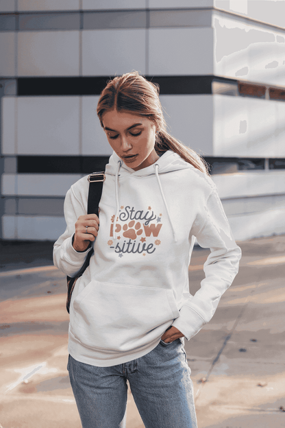 Young woman wearing Printify white Stay Pawsitive Unisex Hoodie with paw print design and kangaroo pocket